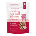 A stand-up pouch of smallbatchdog freeze-dried raw small bites beef recipe dog food, shown on a plain white background. The package is white and dark pink/red with a pink cow illustration and a clear window displaying the dry kibble inside.