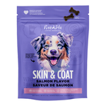 A purple stand-up pouch of RiveAlta Skin & Coat Salmon Flavor dog treats, featuring a large illustration of a blue merle dog on the front. The packaging includes a small graphic of two bone-shaped treats at the top and a pink band near the bottom.
