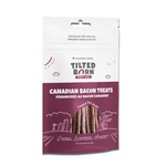 A 50g bag of Tilted Born Pet Co. Canadian Bacon Treats for dogs, featuring a white and deep purple packaging design with illustrations of bacon strips visible through a clear window.