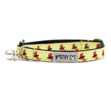 A yellow pet collar with a repeating pattern of red and black cats wearing hats, featuring a silver metal bell and a white brand label that reads 'WORTHY CAT'.