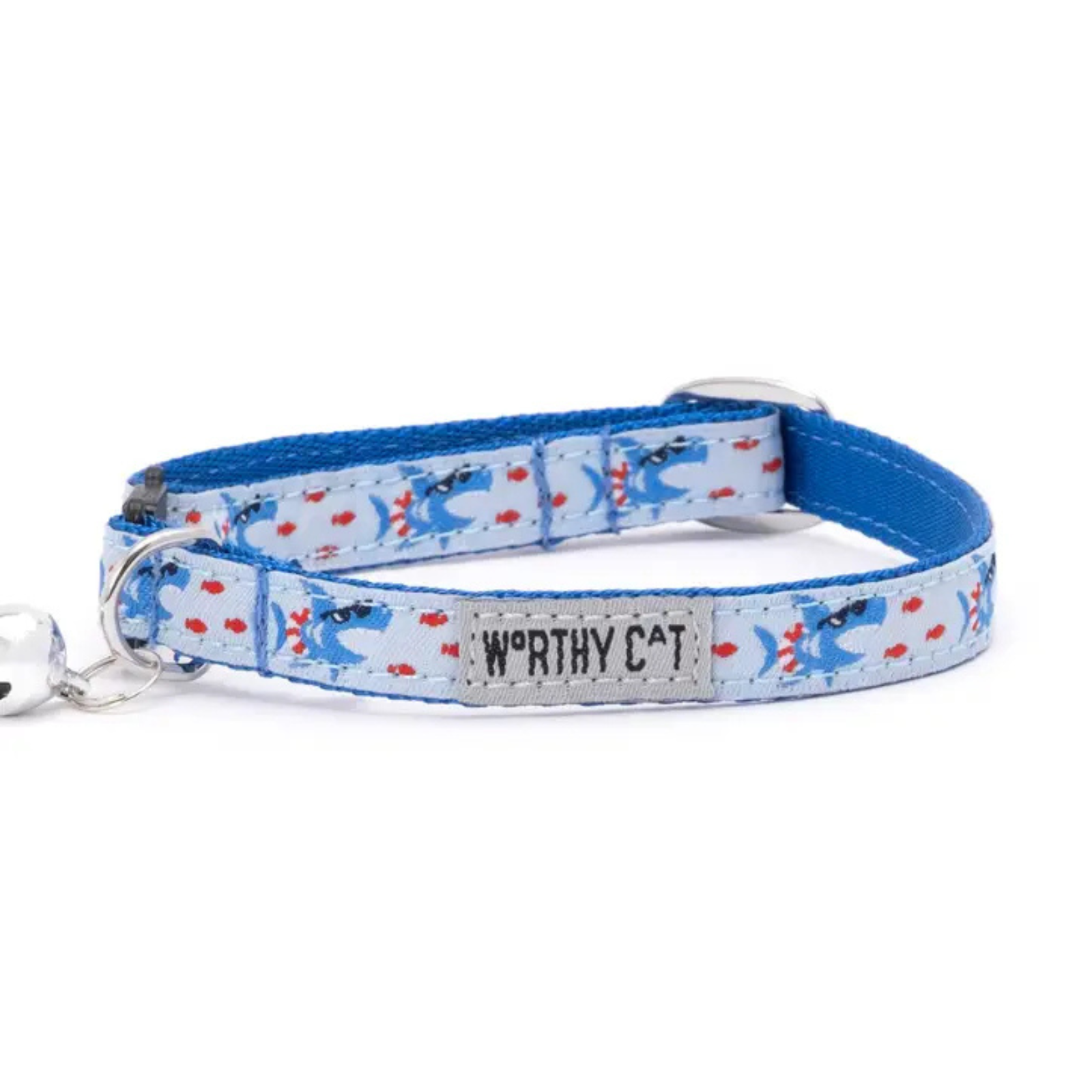 A blue fabric pet collar with a light blue patterned section featuring cartoon cats and red hearts, a silver metal buckle, and a silver bell on the left. A central label reads 'WORTHY CAT'.