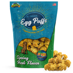 A stand-up pouch of Nitty Witty 'The Original Egg Puff' pet treats in Spring Herb Flavor, shown on a white background with several loose golden-brown popcorn-like treats in front of the bag.