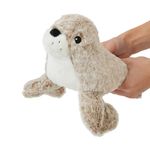 A plush otter toy being held by two human hands against a plain white background.