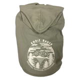 An olive green dog hoodie with a cream-colored circular graphic on the back featuring a mountain and forest design, with the text 'EDDIE BAUER' and 'ORIGINAL OUTDOOR OUTFITTERS'.