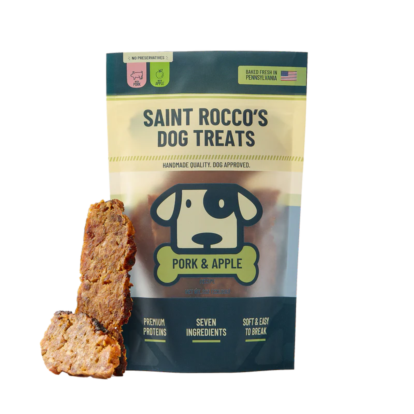 A bag of Saint Rocco's Dog Treats Pork & Apple flavor stands on a white background with two dog treats displayed in front. The packaging is dark teal and cream with a dog logo, and the treats are brown with visible chunks.