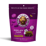 A purple stand-up pouch of Pro Baked by Upcycled Treats Ghoul-Ash Flavor dog treats, featuring a cartoon dog face logo and Halloween-themed graphics including a ghost, witch hat, and cauldron on a white background.