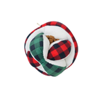 A plush pet toy shaped like a wrapped gift, featuring a red and black buffalo plaid outer fabric, a green and black plaid side panel, a white faux-fur inner lining, and a small brown kibble or toy core visible in the center, isolated on a white background.