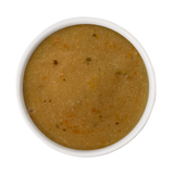 A top-down view of a thick, textured mustard-yellow or ochre-colored puree, such as pumpkin or squash mash, served in a white ceramic bowl against a solid white background.