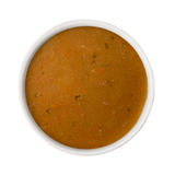 A top-down view of a white bowl filled with a thick, orange-brown soup or sauce, isolated on a white background.