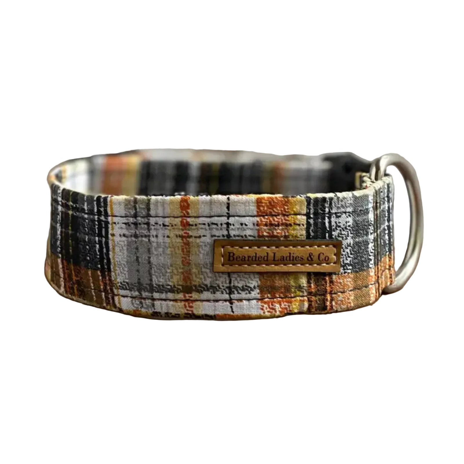 A plaid dog collar with a warm-toned pattern of orange, brown, black, and white, featuring a central leather brand patch that reads 'Bearded Ladies & Co.' and a silver metal ring, displayed on a rustic wooden surface.
