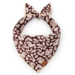 A brown and beige patterned pet bandana with a tie-on bow, featuring a repeating leaf and floral print, shown on a plain white background.