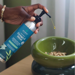 Hand holding a bottle of Pet Releeve Omega-3 product over a green bowl with pet food.