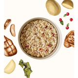 A bowl of cooked grain or rice with visible red berries, surrounded by illustrated food ingredients including potatoes, a grilled piece of meat, a lemon wedge, green beans, and cranberries on a light background.
