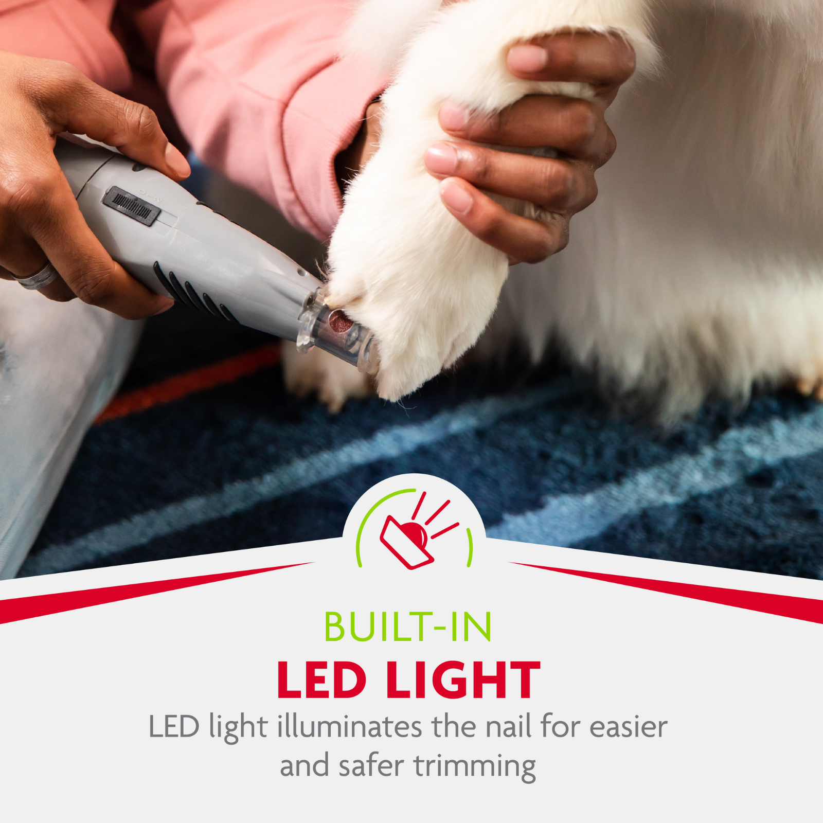 Person using a pet nail trimmer with a built-in LED light on a dog's paw.
