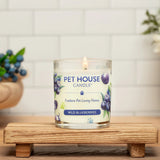 Pet House Candle labeled 'Wild Blueberries' on a wooden stand with a blurred background