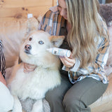 Woman applying a product to a dog's paw on a couch