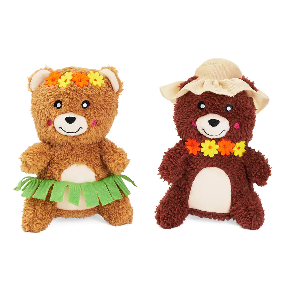 Two teddy bears dressed in hula and safari outfits on a white background
