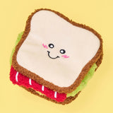 Plush toy shaped like a sandwich with a smiley face on a yellow background