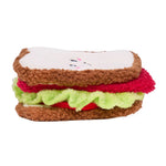 Plush toy designed like a sandwich with brown bread, white cheese, red meat, and green lettuce on a white background.