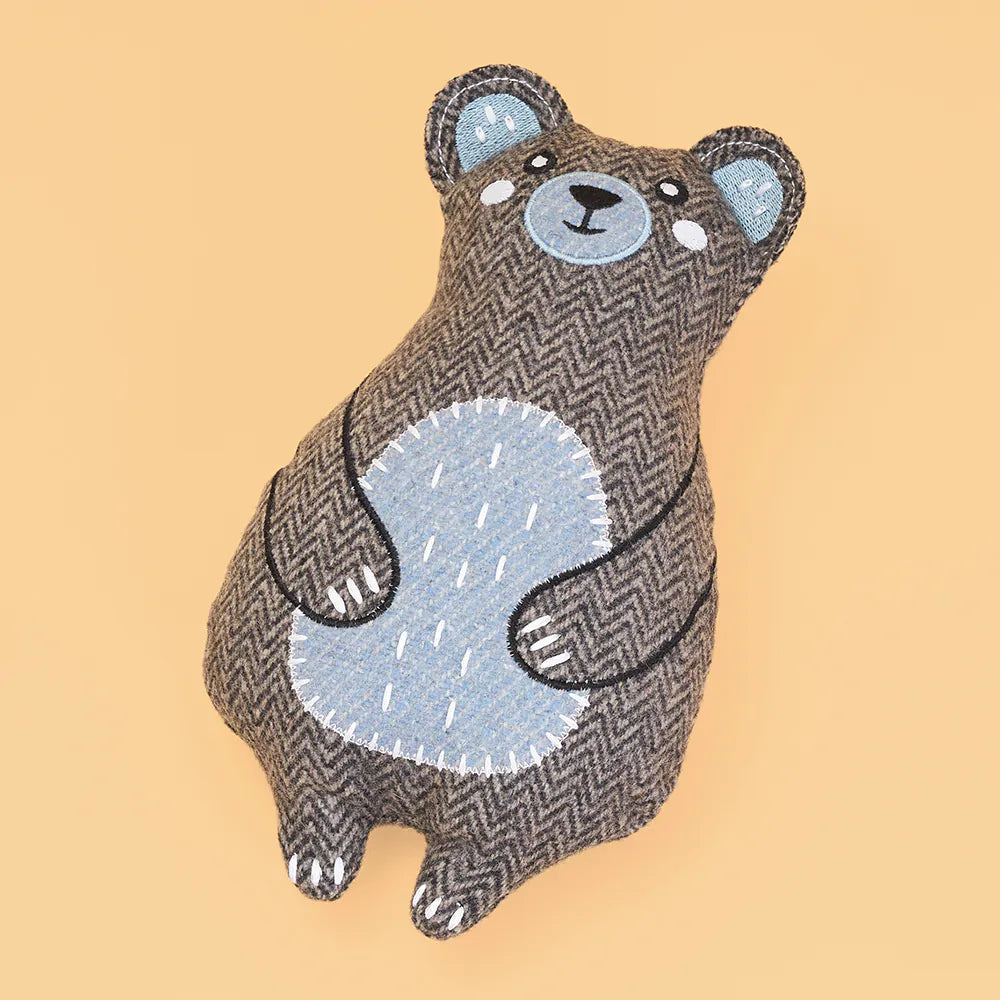 Stuffed bear toy with a herringbone pattern on a beige background