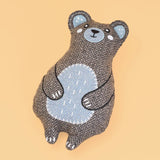 Stuffed bear toy with a herringbone pattern on a beige background