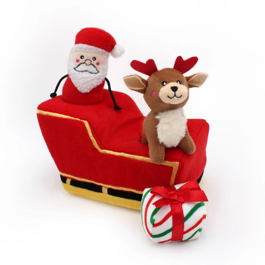 Plush Santa Claus in a red sleigh with a reindeer and a gift on a white background