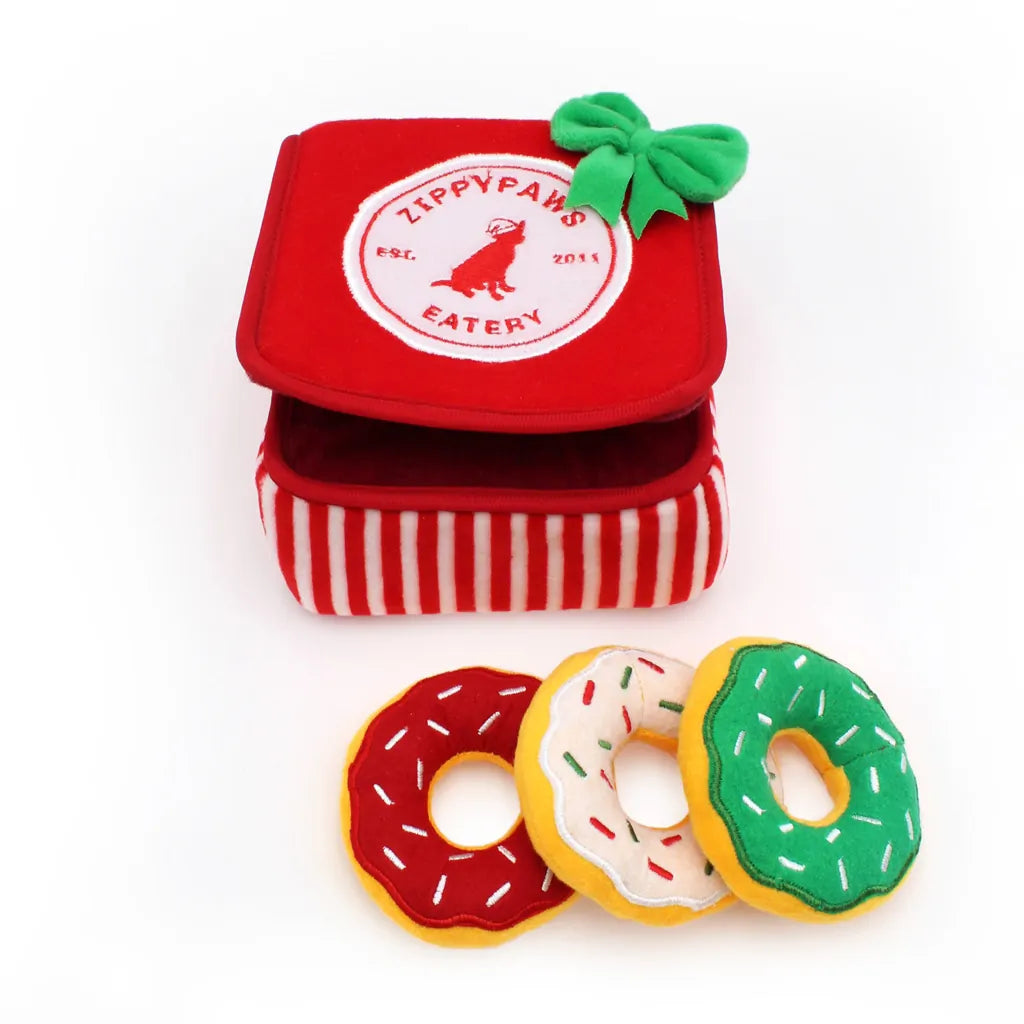 Red and white striped container with 'ZippyPaws Eatery' logo and three donut-shaped pet toys in red, white, and green.