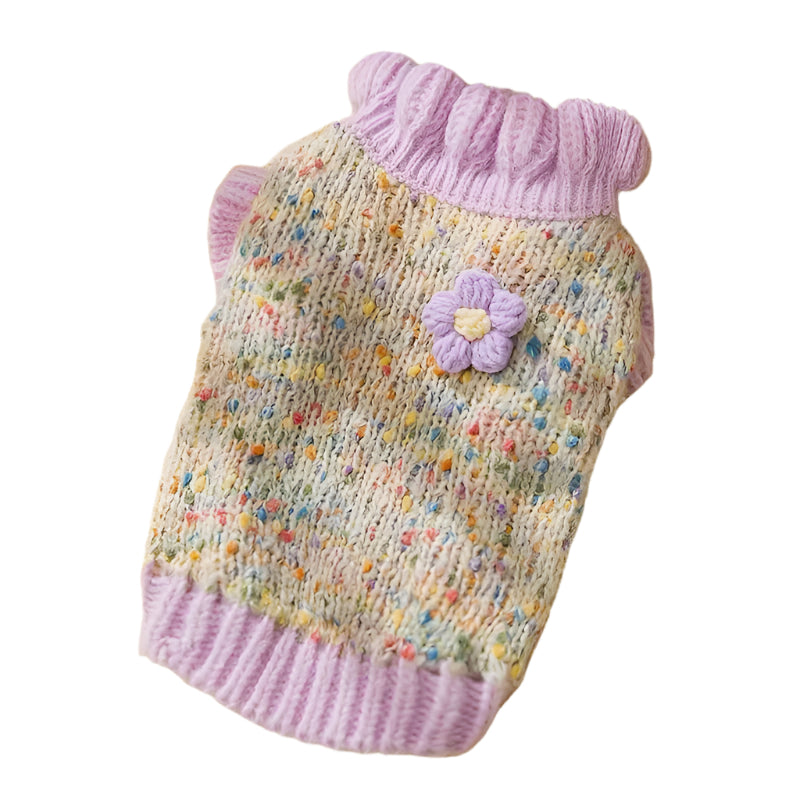 Knitted pet sweater with a flower decoration on a yellow textured surface