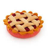 A plush dog toy shaped like a pie, featuring a beige woven lattice top, red fruit filling, and a pink crust, isolated on a white background.