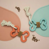 Two dog toys with rope handles on a pink and teal background.