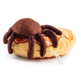 Plush toy resembling a spider on a hot dog bun with mustard, on a white background