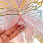 Butterfly wings with pink and gold details held by a hand
