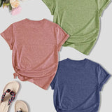 Three t-shirts in pink, green, and blue on a light surface with flip-flops and flowers.