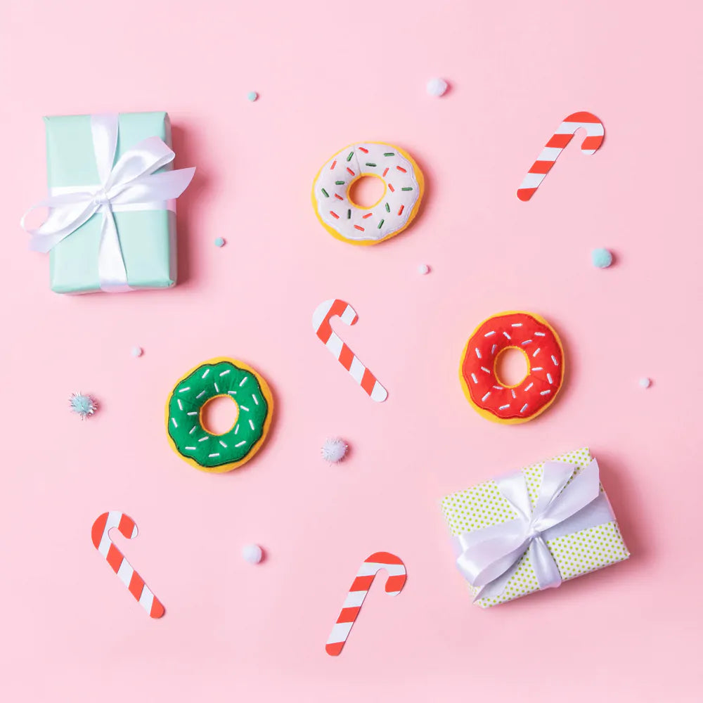 Colorful donuts, candy canes, and gift boxes on a pink background