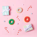 Colorful donuts, candy canes, and gift boxes on a pink background