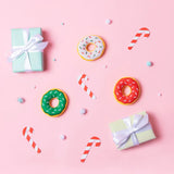Colorful donuts, candy canes, and gift boxes on a pink background