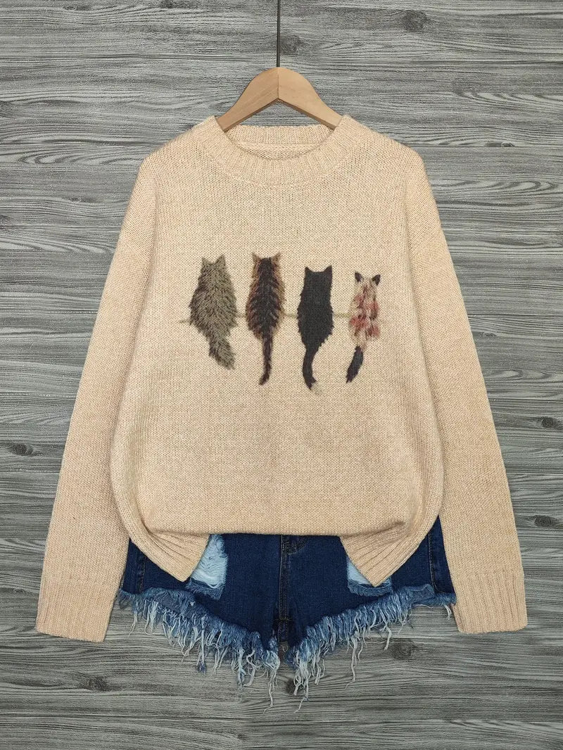Beige sweater with cat illustrations on a wooden hanger against a wooden background