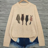 Beige sweater with cat illustrations on a wooden hanger against a wooden background