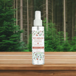 Pet House Freshening Room Spray bottle on a wooden surface with a forest background