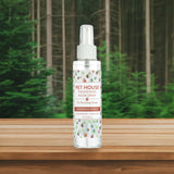 Pet House Freshening Room Spray bottle on a wooden surface with a forest background