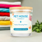 Pet House Candle labeled 'Sunwashed Cotton' with a stack of folded clothes in the background.