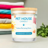 Pet House Candle labeled 'Sunwashed Cotton' with a stack of folded clothes in the background.