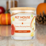 Pet House Candle labeled 'Apple Cider' with pumpkins and pinecones in the background