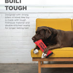 Dog chewing on a red toy with text about durability on a yellow couch.