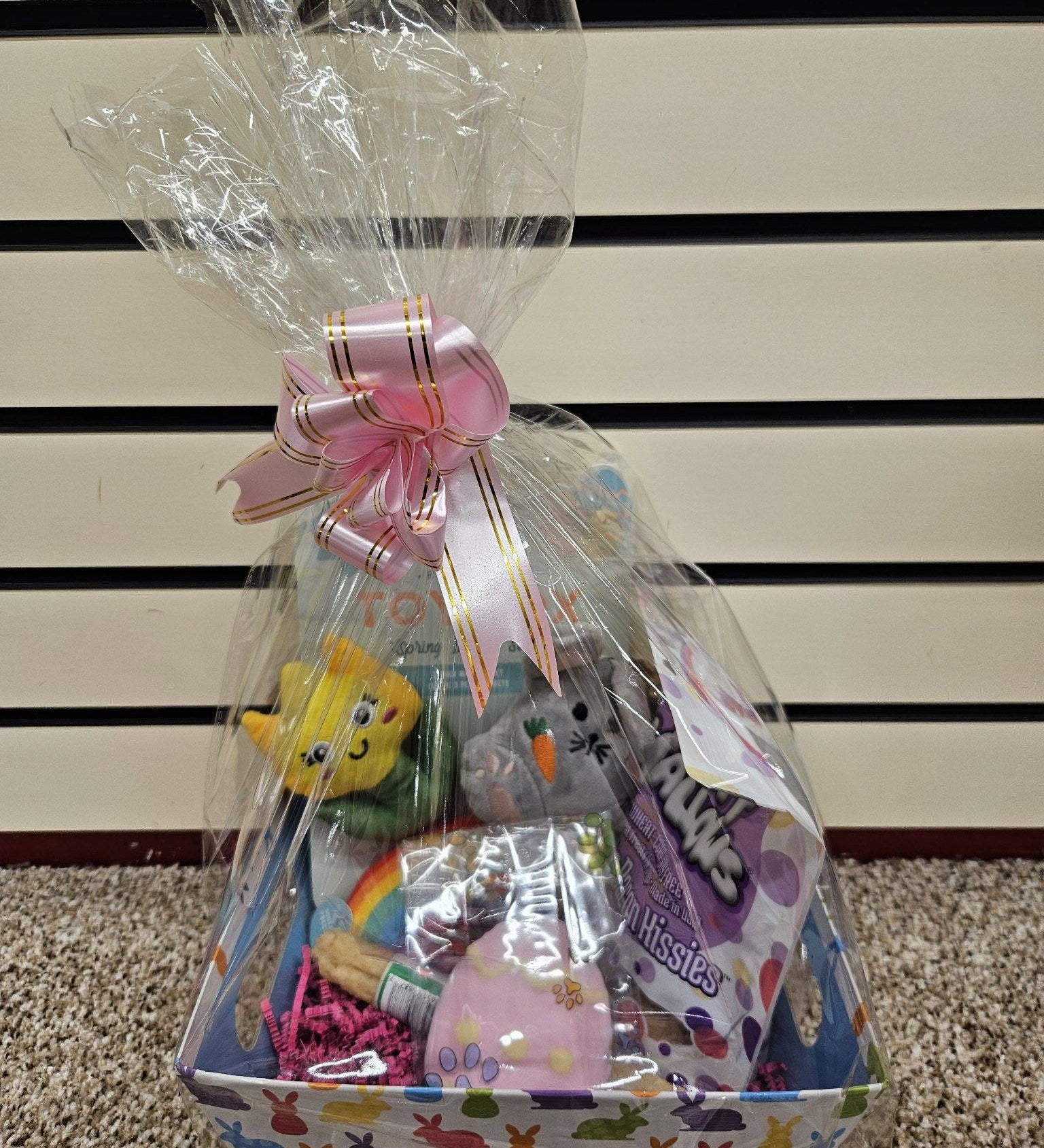 A Prefilled Easter Basket for small to medium dogs, containing various toys and treats, wrapped in clear plastic with a ribbon.