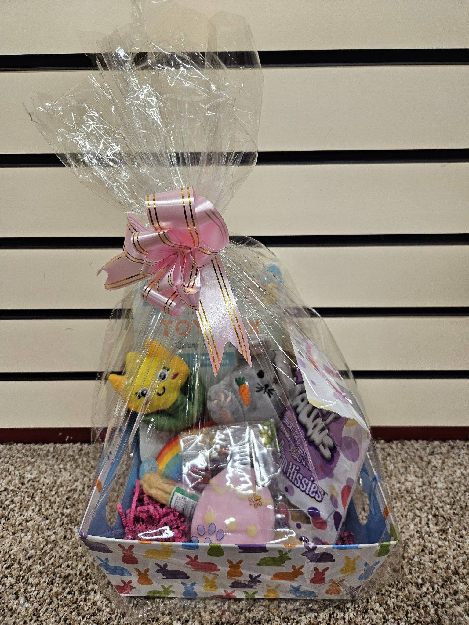 A Prefilled Easter Basket for small to medium dogs, containing various toys and treats, wrapped in clear plastic with a ribbon.