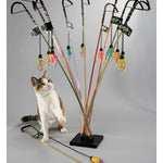 Cat playing with a colorful cat toy stand on a gray background