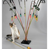 Cat playing with a colorful cat toy stand on a gray background