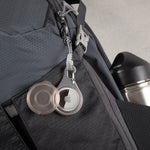 Close-up of a backpack with Apple AirTag keychain attached on a gray background
