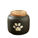 Black pet urn with paw prints on a wooden surface
